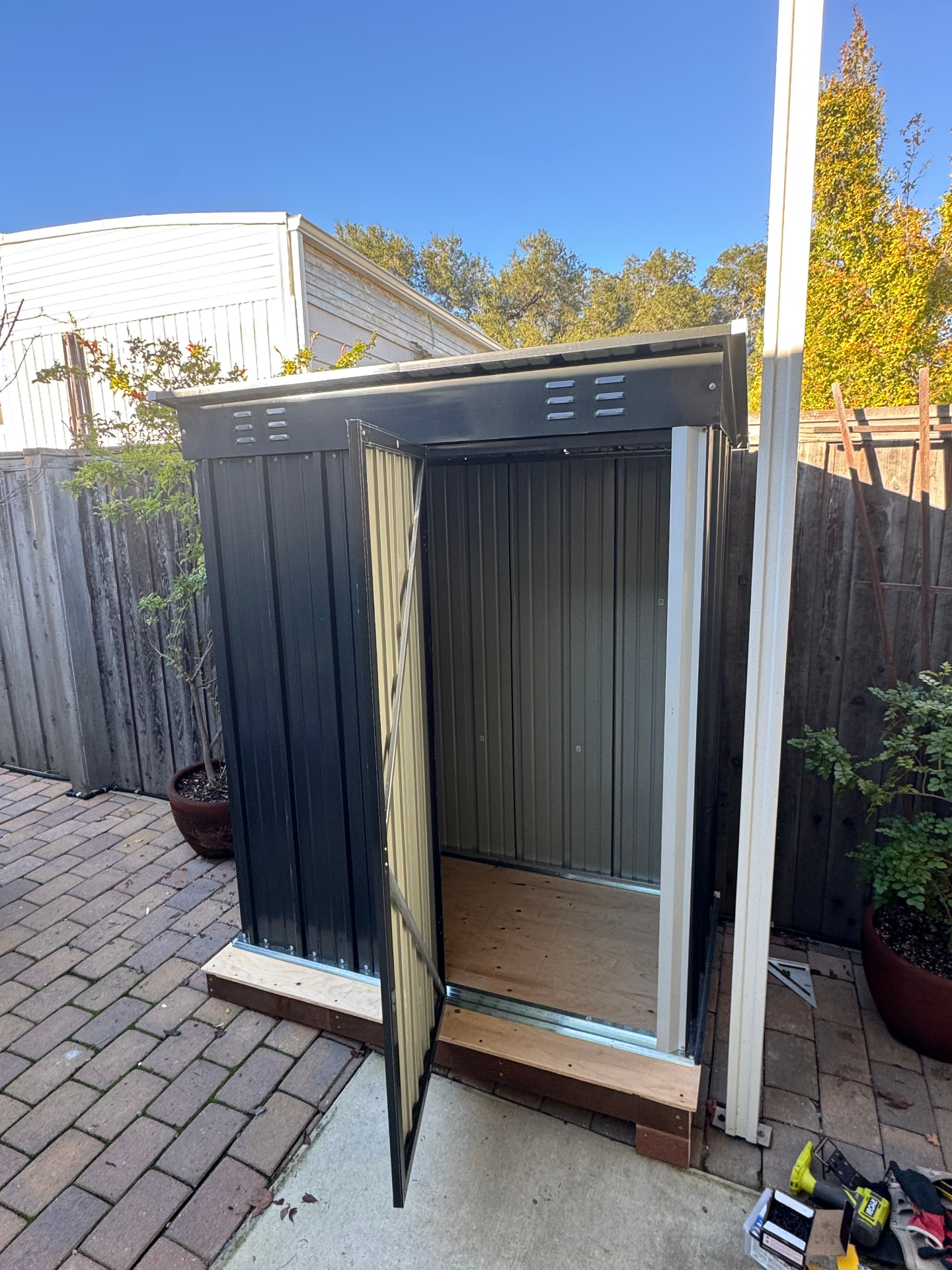 Compact metal shed built on a level timber base in a backyard patio